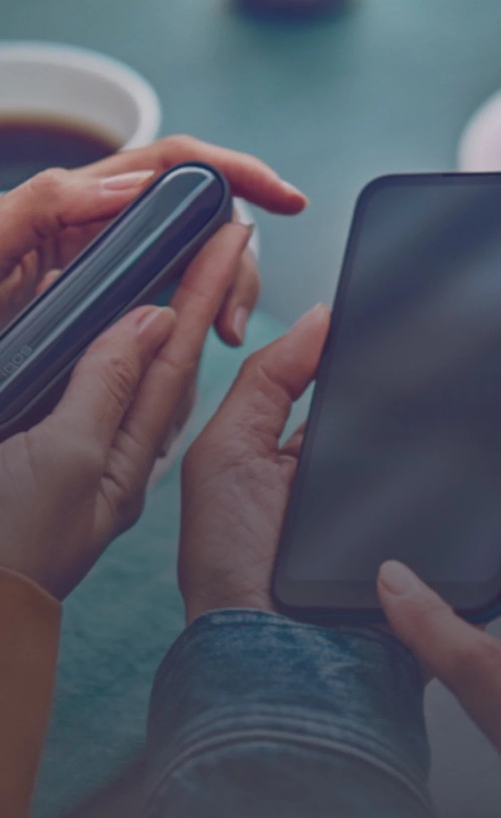 شخص يستخدم جهاز IQOS، حاملاً هاتف.